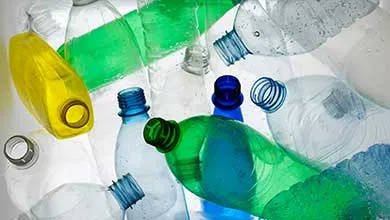Pile of empty plastic bottles in green, blue, yellow, and clear.